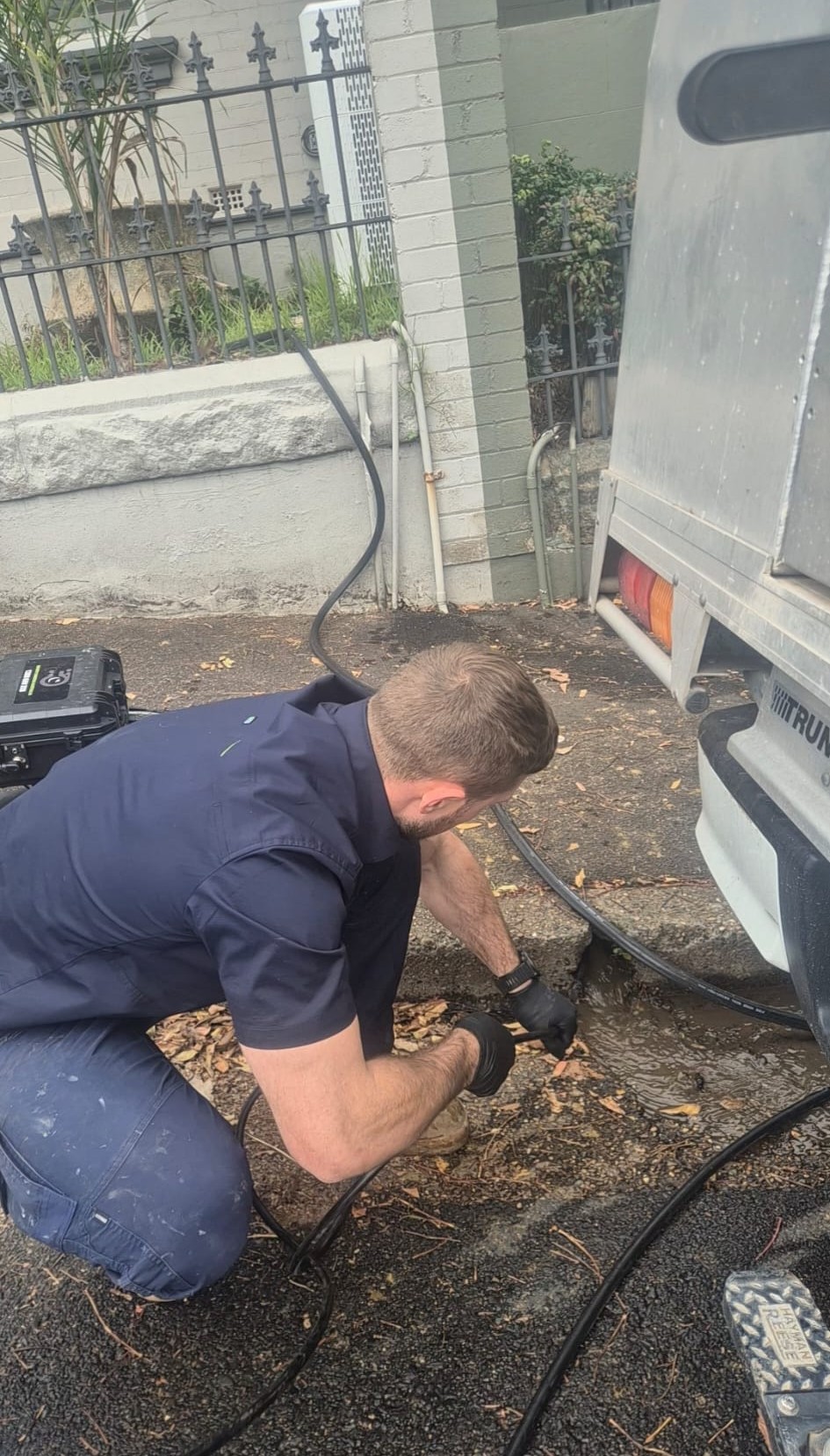 Jayden clearing a blocked drain at the kerb beside his ute in the Hills District
